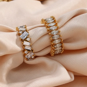 Detail shot of golden earrings with zircon inlay on luxury champagne satin fabric
