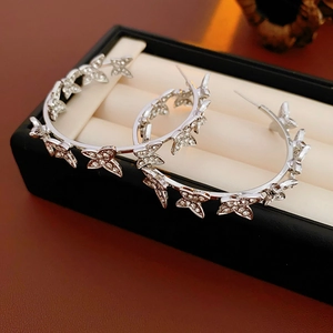 Gros plan de boucles d'oreilles C papillon argenté avec zircons brillants sur coussin
