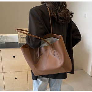 Brown leather large tote bag shown on a model's shoulder for size reference