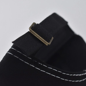 Dettaglio del cappello in cotone nero con fibbia in metallo vintage e cuciture bianche