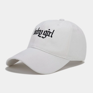 Close-up of gothic 'Babygirl' black embroidery on a white cotton baseball cap fabric