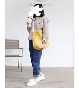 Detail of bright yellow canvas tote bag with wide white shoulder strap on casual outfit
