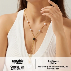 Detailed view of long gold snake chain necklace with faux pearls and black ring slide