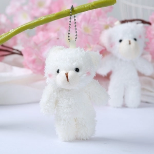 Close-up of white plush teddy bear with pink blush hanging on a green branch