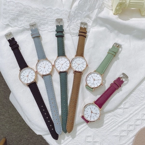 Orologi da donna minimalisti con cinturini in pelle colorata su sfondo di pizzo