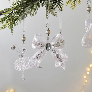 Elegant white acrylic Christmas ornaments with snowflake and bow tie on snowy pine branch