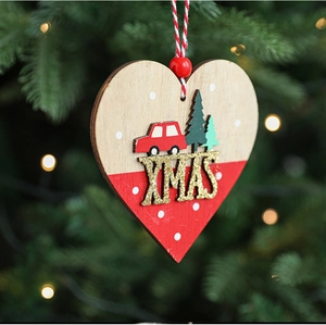 Detail of wooden heart ornament with red car and XMAS text on a lit Christmas tree