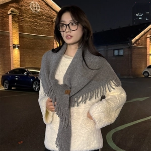 Elegant grey knitted shawl scarf with tassels styled over a white coat in city street view