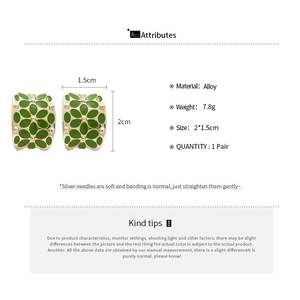Detail of C-shaped green enamel flower earrings with gold beaded edges and alloy base