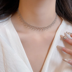 Macro shot of silver woven hollow mesh necklace on collarbone over white silk