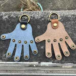 Close-up of blue and brown palm-shaped leather keychains with metal snaps and rings