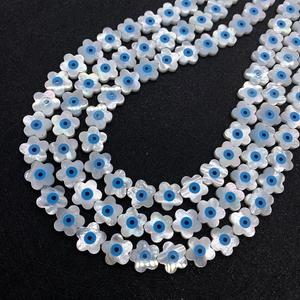 Natuurlijke schelpkralen in bloemvorm met blauw boze oog op zwarte ondergrond