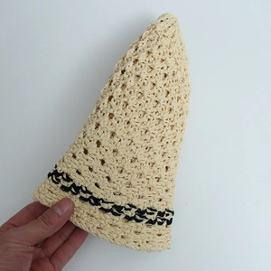 Detailed macro view showing the flexible straw texture and black wavy trim of the sun hat