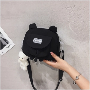 Detail of black canvas crossbody bag with bear ears and a plush bear pendant