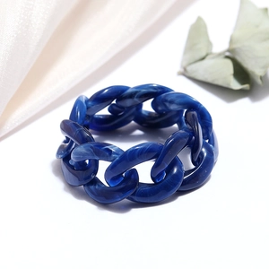 Macro shot of dark blue resin chain ring with marble texture on white and silk backdrop