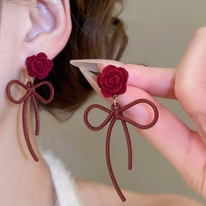 Detail view of vintage red flocked rose earrings with textured bow pendant drop