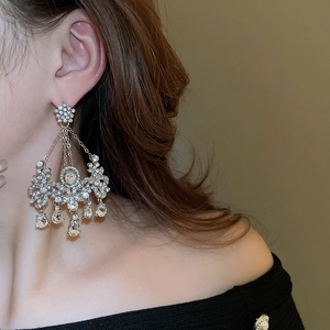 Gros plan de boucles d'oreilles lustres étincelantes avec strass fleurs et franges
