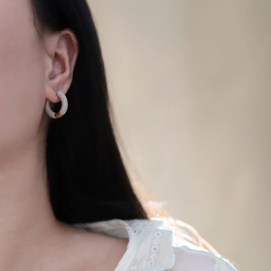 Detail of 18K gold plated hoop earring featuring cream grey resin contrast design