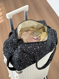 Dettaglio della borsa da viaggio trapuntata a fiori fissata al manico del trolley