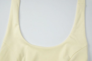 Detail of light yellow knitted halter top showing U-shaped neckline and ribbed texture