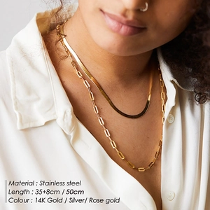 Detail of layered stainless steel snake and paperclip chain necklaces on neck