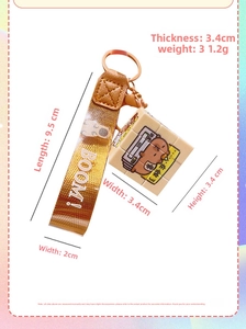 Detail view of a mini Capybara cube keychain with brown woven strap and orange leather trim