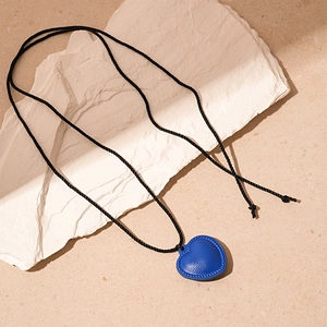 Détail du pendentif cœur en cuir bleu avec texture tressée sur un collier rétro long
