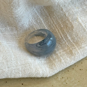 Macro detail of oval gray marble resin ring on a textured fabric surface background