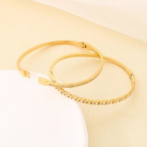 Dettaglio di due bracciali in acciaio inossidabile dorato con strass scintillanti