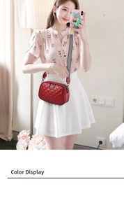Red quilted crossbody bag with wide striped strap shown on a model in a cozy indoor setting