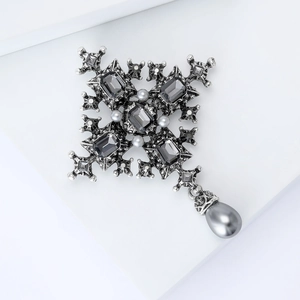 Detailed view of Baroque cross brooch featuring grey pearls and faceted dark gemstones