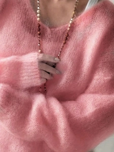 Close-up of pink mohair knit sweater featuring soft fluffy texture and beaded necklace
