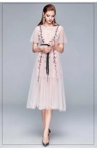 Détail de broderie florale sur robe en tulle rose avec ceinture noire élégante
