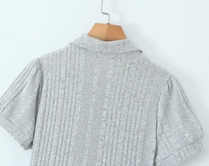 Dettaglio vestito in maglia grigia con trama a costine e maniche corte a sbuffo
