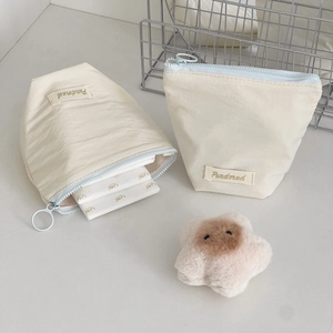 Minimalist cream-colored nylon makeup bag set with blue zippers and gold lettering