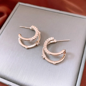 Close-up of double-layered rose gold C-shaped earrings with zircon inlay and bead details