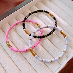 Dettaglio di bracciali a segmenti di bambù in smalto nero, rosa e lilla su velluto