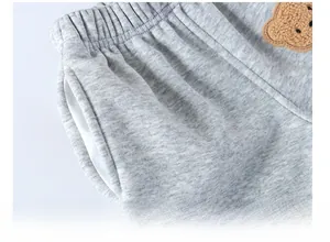 Detail of grey kids' joggers featuring elastic waistband and cute teddy bear patch