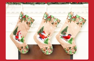 Three decorative linen Christmas stockings with Santa and snowman hanging on a fireplace