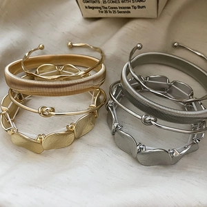 Detailed close-up of gold and silver irregular metallic bangles on soft beige fabric