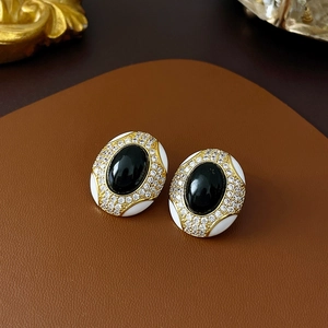 Macro shot of vintage black gemstone earrings with gold accents and zircon inlay