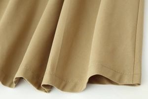Gros plan détaillé sur la texture du tissu kaki et la double couture sur le bord du vêtement