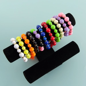 Détail d'un lot de bracelets en perles multicolores sur un support professionnel en velours