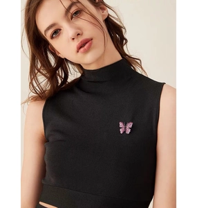 Detail of a pink butterfly brooch with crystals on a black high-neck top for women
