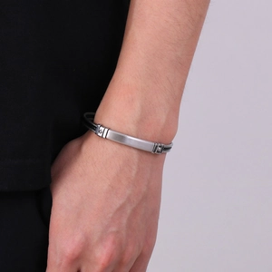 Macro detail of men's steel cable bracelet with brushed metal plate on male wrist