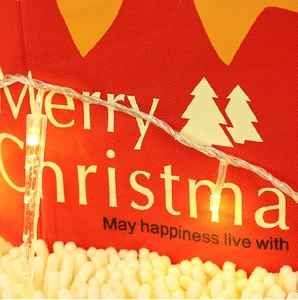 Close-up of warm white LED icicle lights hanging over a red festive Christmas gift bag