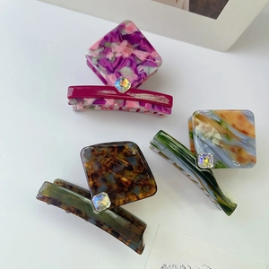 Detail view of acetate claw clips with square rhinestones and elegant marble textures