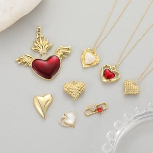 Baroque gold-plated heart pendants with red enamel and angel wings on stone background