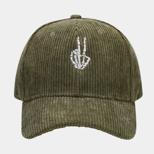 Close-up of white skeleton hand embroidery on green corduroy baseball cap texture