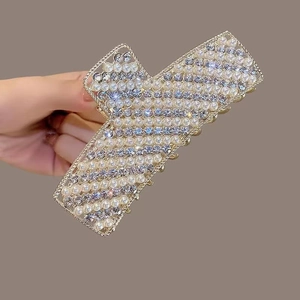 Macro detail of large square metal hair claw with rows of pearls and sparkling rhinestones